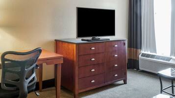 Una habitación de hotel con escritorio, silla, televisor y cómoda.