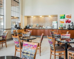 Un café moderno con mobiliario de madera, pared decorada y una barra con diferentes productos alimenticios.