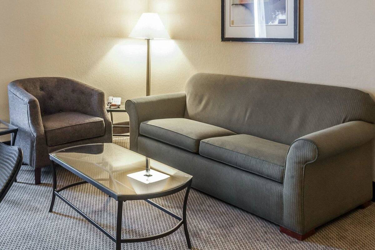 A living room with a grey sofa, a brown armchair, and a glass coffee table.