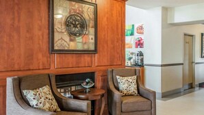 A lobby with two armchairs, a small round table, and a decorative wall piece. - Quality Inn & Suites Albuquerque West (Albuquerque)