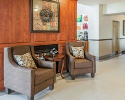 Un hall con dos sillones, una mesita redonda y un elemento decorativo en la pared.