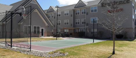 A building with a basketball court and a tennis court.