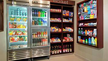 A refrigerated display with various food items and beverages, and adjacent shelves stocked with snacks and household products.
