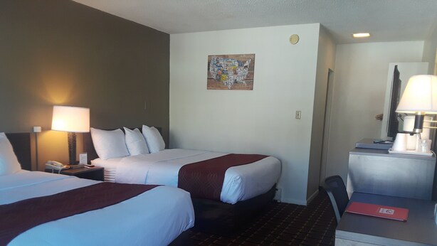 A hotel room with two beds, a desk, a chair, a lamp, a phone, and a wall decoration. - Econo Lodge Colorado Springs Downtown (Colorado Springs)