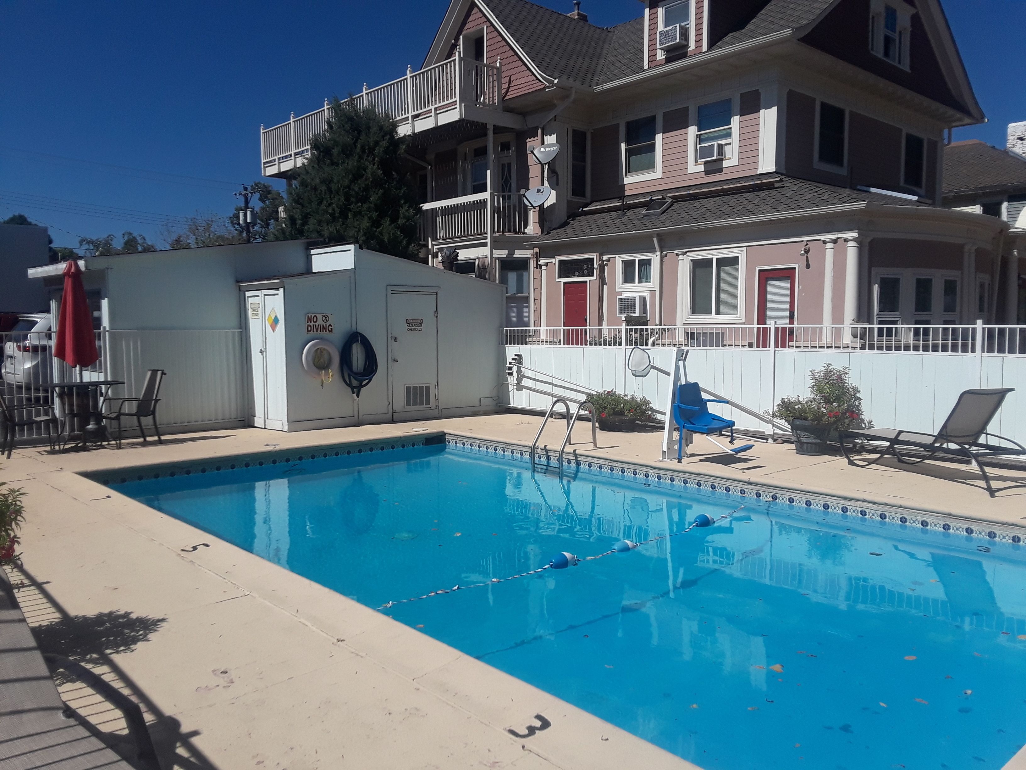 A swimming pool with a diving board, lounge chairs, and a no diving sign.
