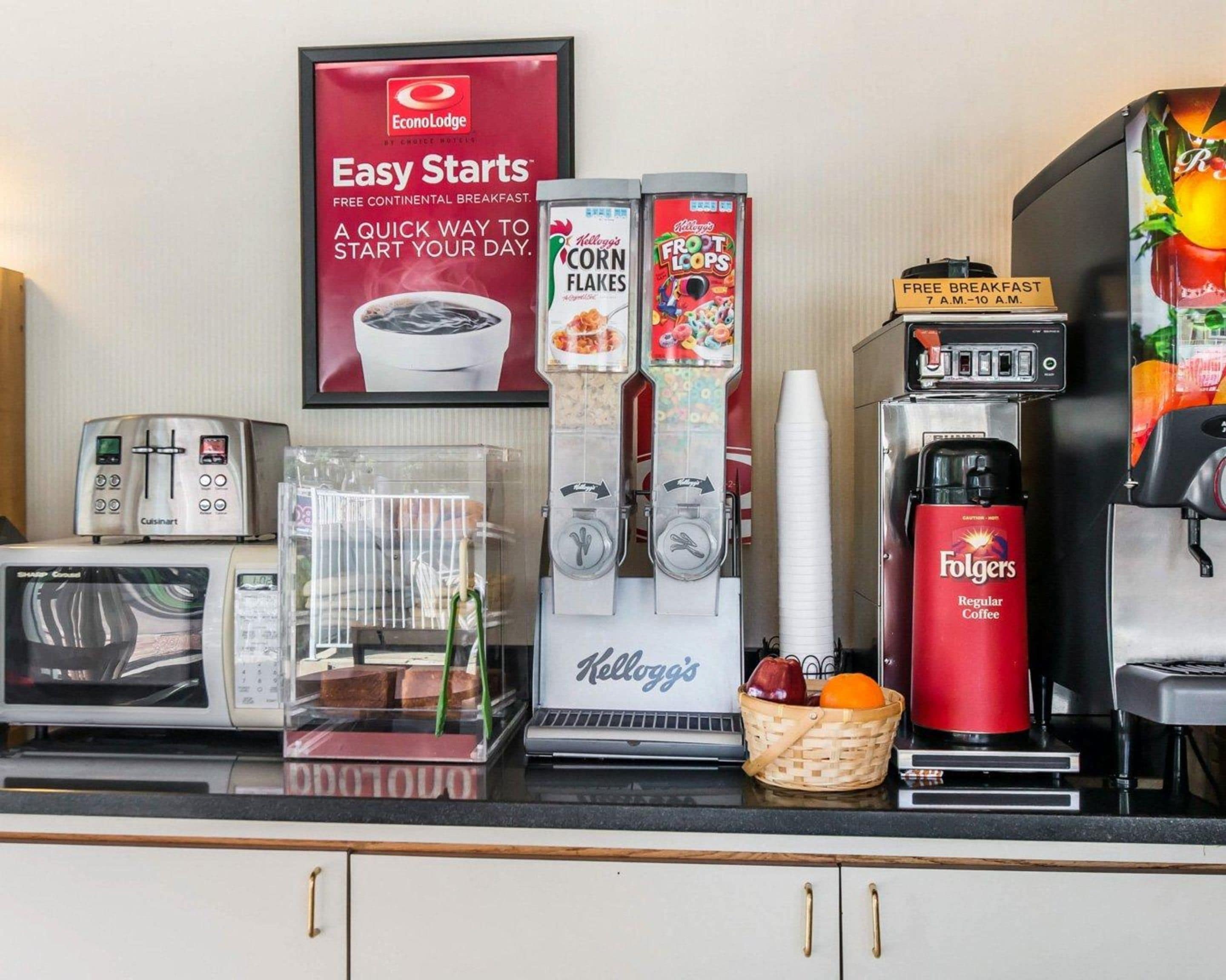 Una colazione con diversi macchinari per caffè, tra cui Folgers e Kellogg's, e un cartello che pubblicizza la colazione continentale gratuita.