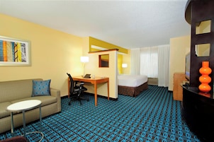 Habitación de hotel con sofá, una mesita, escritorio, cama y televisor.
