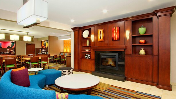 A hotel lobby with a fireplace, seating area, and a bar. - Fairfield Inn & Suites by Marriott Colorado Springs South (Colorado Springs)