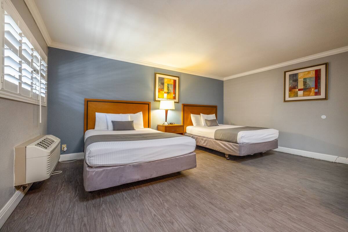 Una camera d'albergo con due letti, un termosifone e opere d'arte alle pareti.