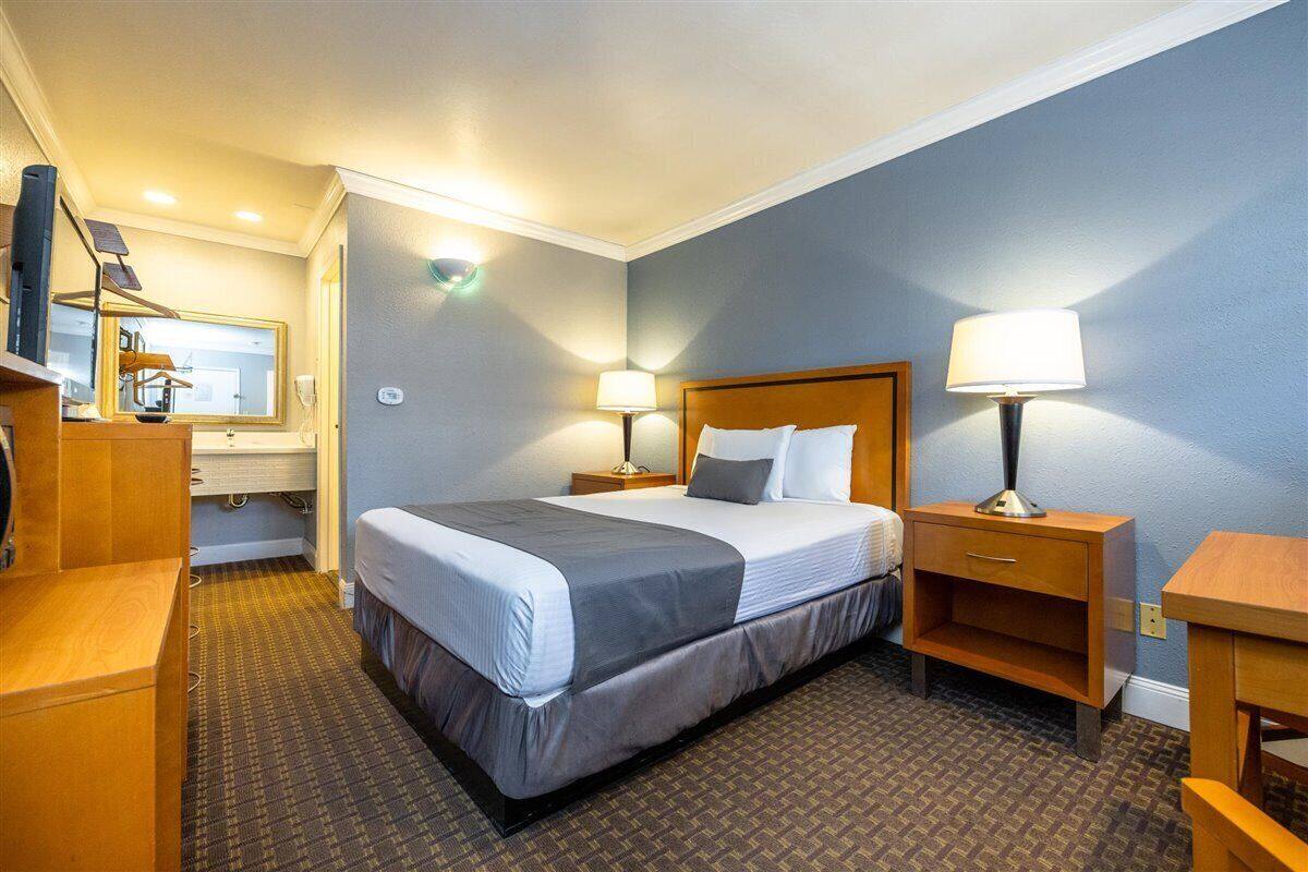 Una camera d'hotel con un letto, comodini, una scrivania, uno specchio e un armadio.