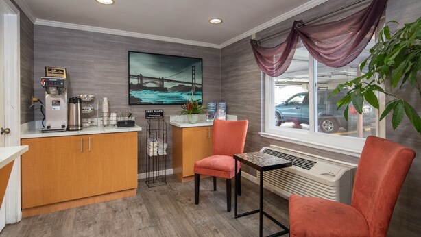 A modern kitchen with a coffee machine, a refrigerator, and a sink. There is a window with a view of a car and a plant on the right. - SOMA Park Inn – Civic Center (San Francisco)