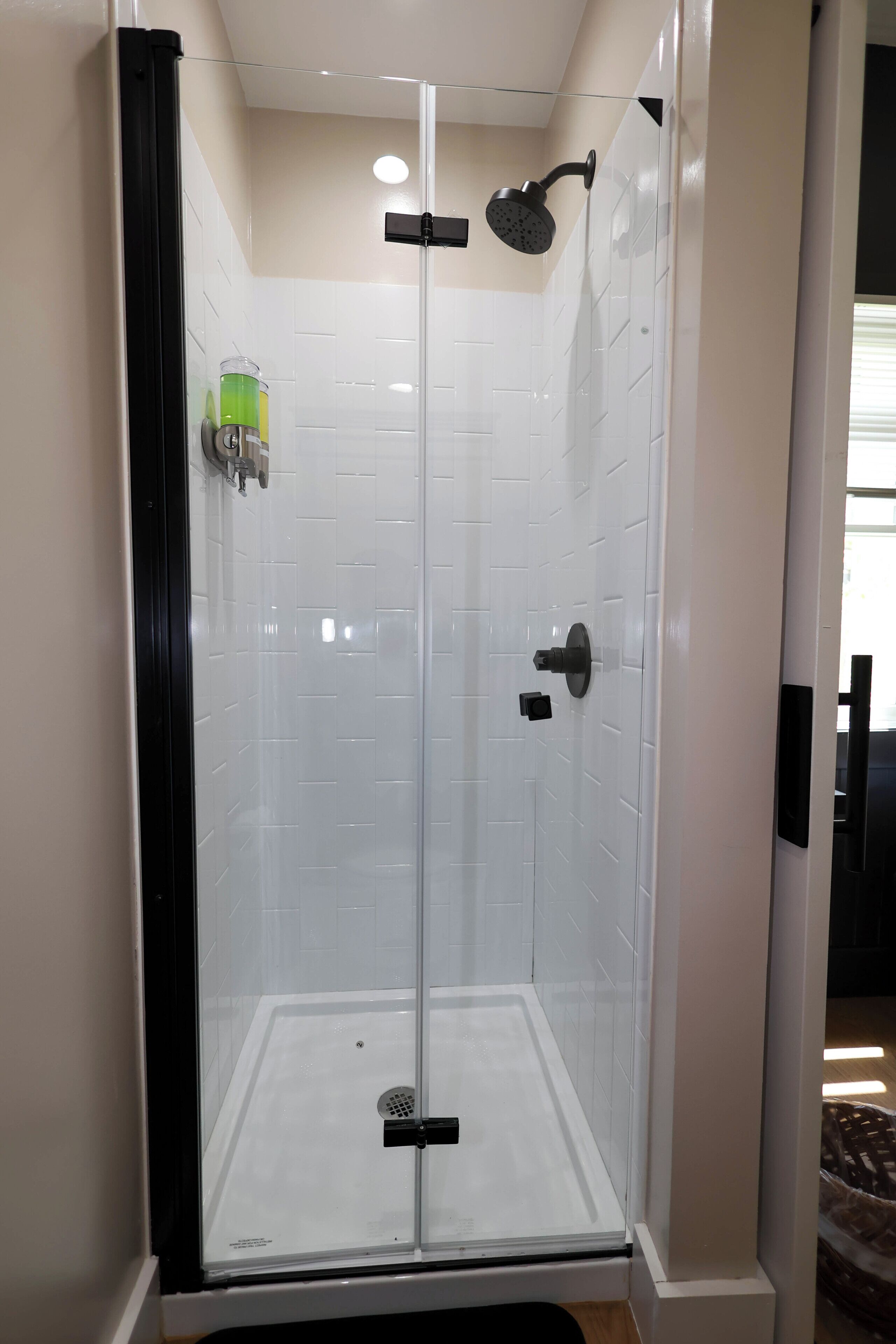 A glass-enclosed shower stall with a handheld showerhead and a wall-mounted faucet.