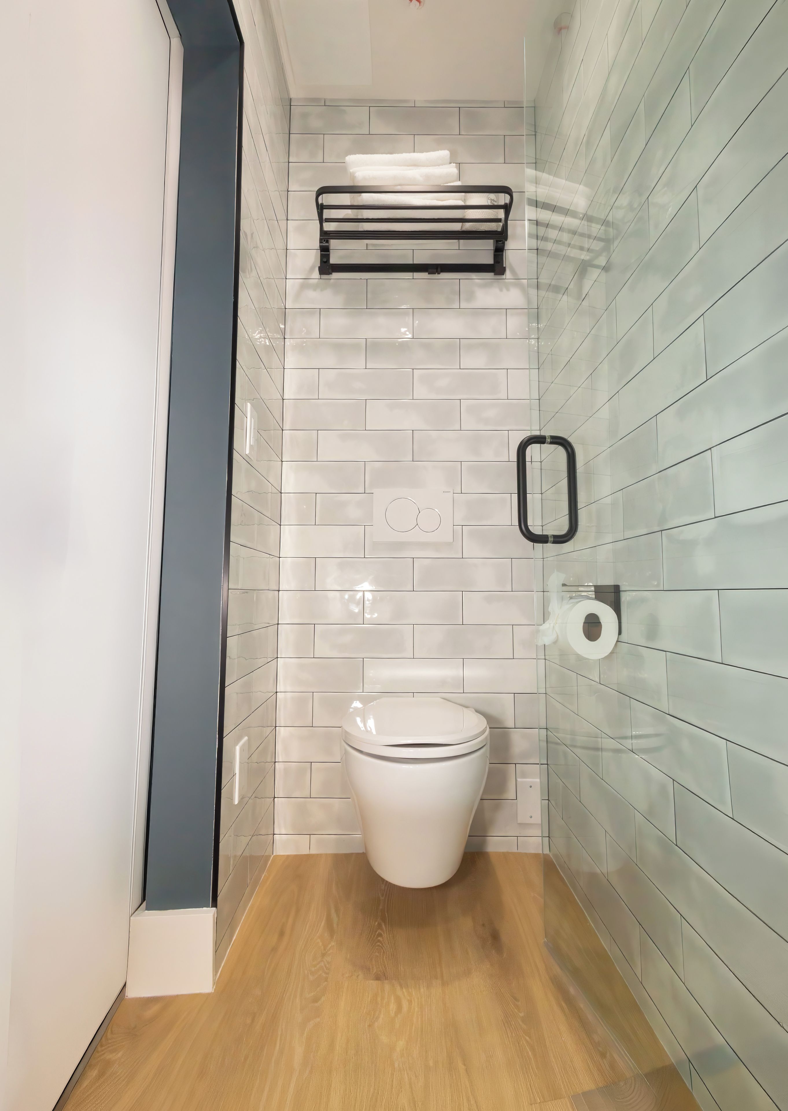 A modern bathroom with a white toilet, a towel rack, and a toilet paper holder on the wall.