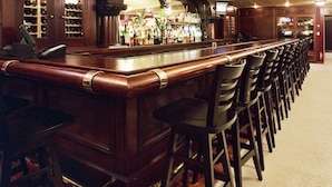 A bar area with a long counter, multiple bar stools, and a ceiling fan. - San Remo Hotel (San Francisco)