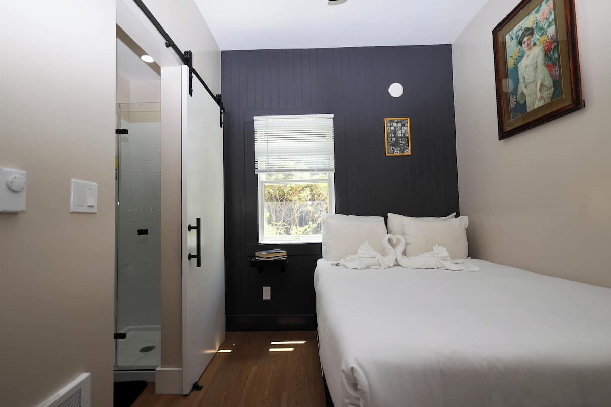 Un dormitorio con cama, ventana, puerta y zona de ducha.