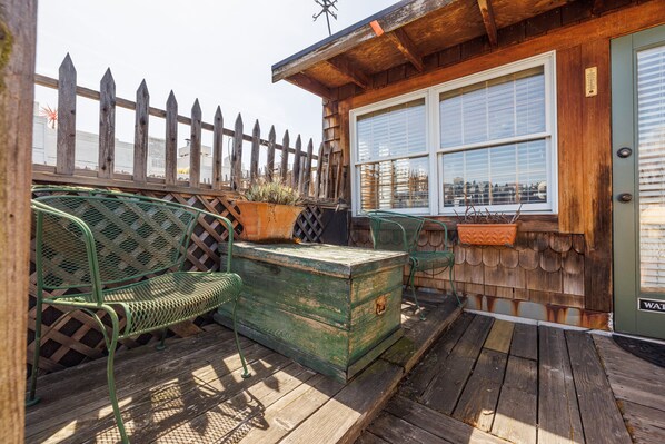 A wooden deck with metal chairs and a green chest of drawers.