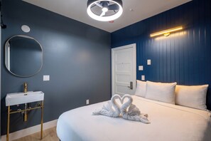 A hotel room with a bed, a round mirror, a white sink, and a wall-mounted light fixture.