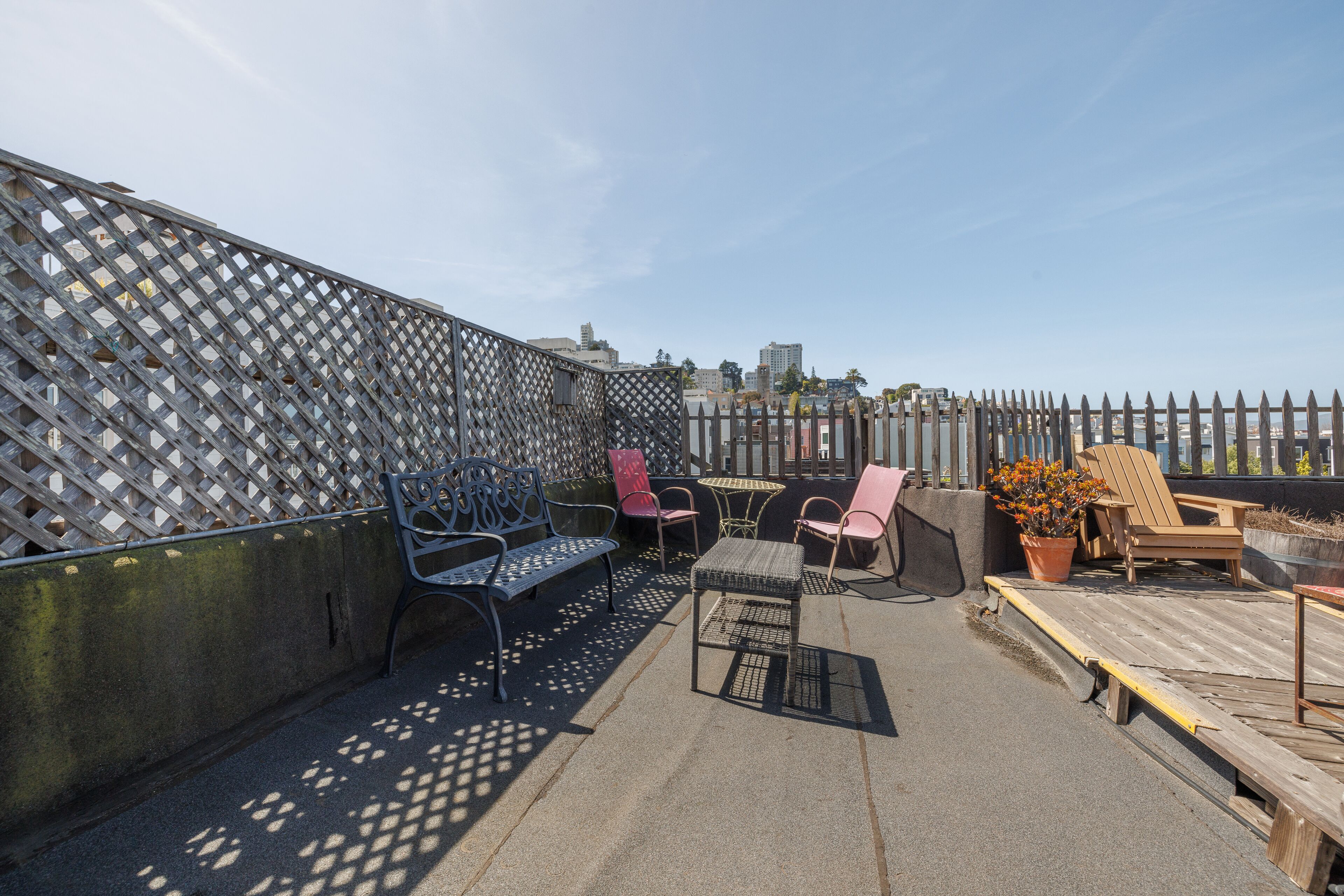 A rooftop patio with outdoor furniture, a lattice fence, and a view of the cityscape.