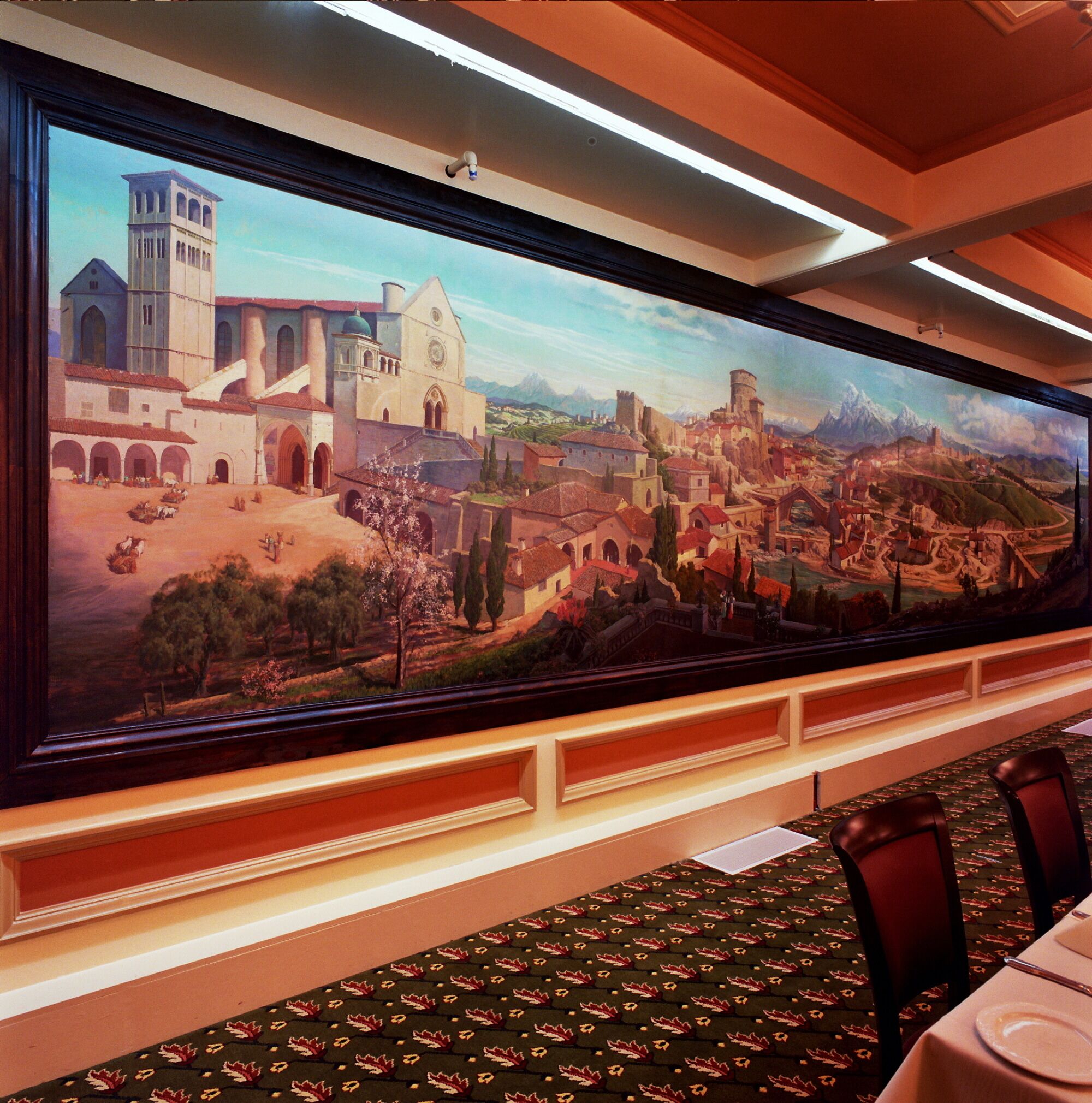 A large mural of a historical town scene with buildings and a mountain backdrop.