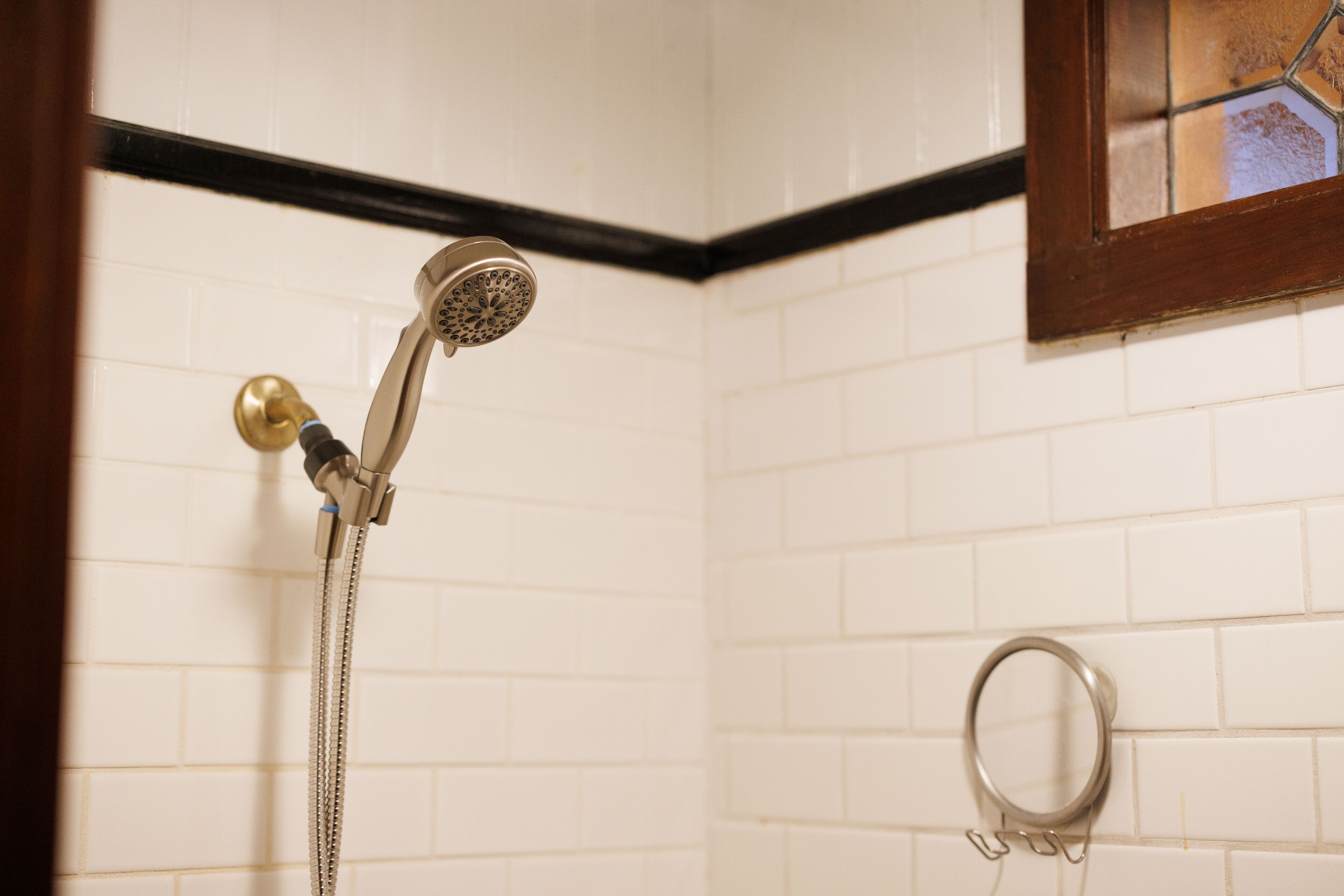 A shower with a handheld showerhead and a wall-mounted faucet.
