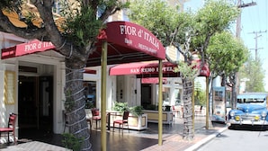 A street view of a bar and restaurant named "Fior d'Italia" with outdoor seating and a vintage blue car parked nearby. - San Remo Hotel (San Francisco)
