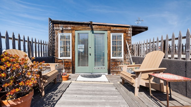 A wooden deck with a door, a bench, a chair, and a table. - San Remo Hotel (San Francisco)