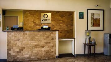 A hotel reception area with a brick counter, a digital display, and a framed artwork on the wall.