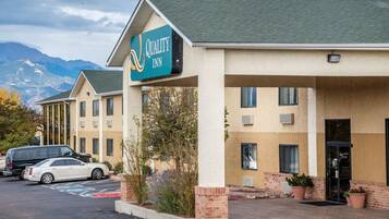 A Quality Inn hotel with a two-story building, a parking lot, and mountains in the background.