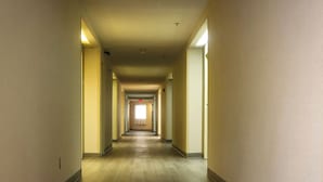 A long, narrow hallway with wooden flooring and light-colored walls.