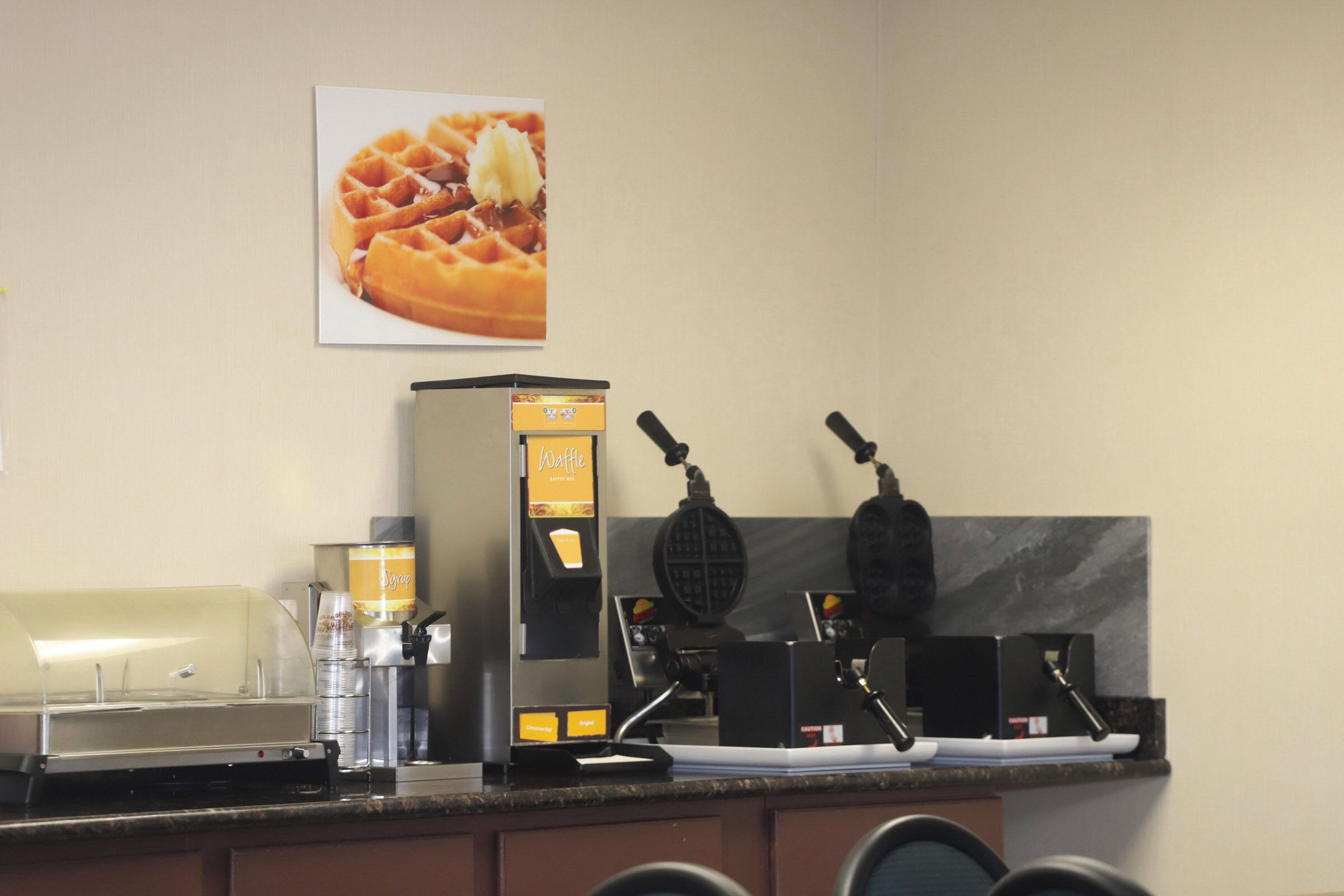 A waffle station with a waffle maker, a waffle dispenser, and a waffle box.