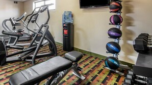 A gym with treadmills, a bench, a water dispenser, and a wall-mounted TV.