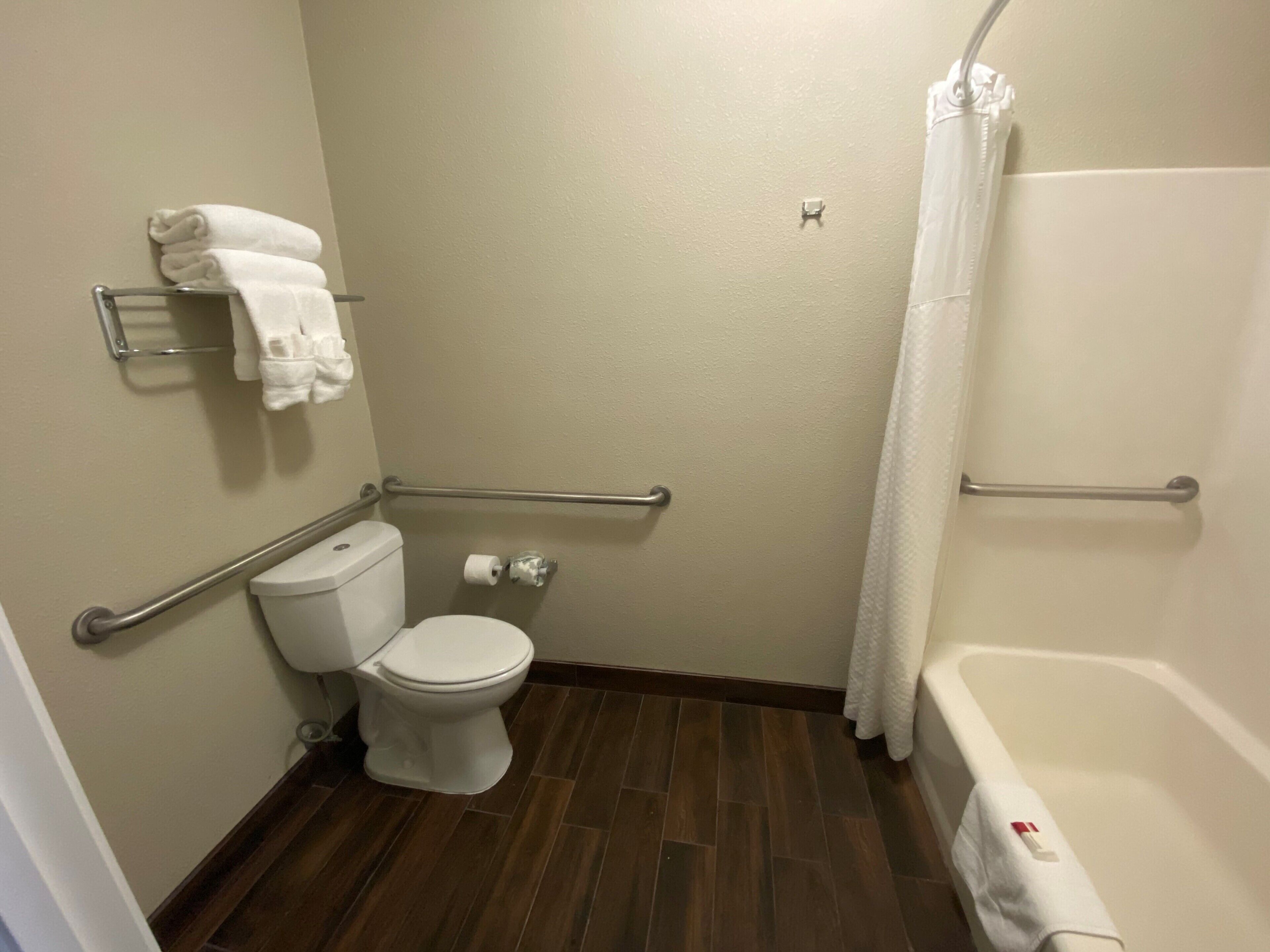 A small, clean bathroom with a toilet, a shower with a grab bar, and a towel rack.