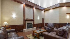 Una sala de estar con sofás de cuero, una mesa de centro de madera, una chimenea y apliques de pared.