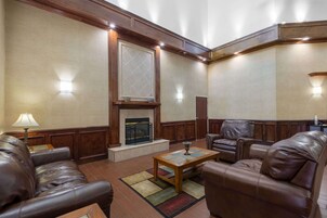 Una sala de estar con sofás de cuero, una mesa de centro de madera, una chimenea y apliques de pared.