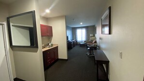 Una habitación de hotel con kitchenette, comedor y sala de estar.