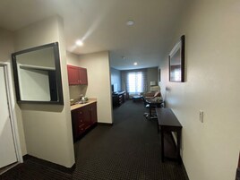 Una habitación de hotel con kitchenette, comedor y sala de estar.