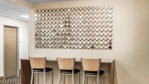 A bar area with three high stools and a wall decorated with circular mirrors.