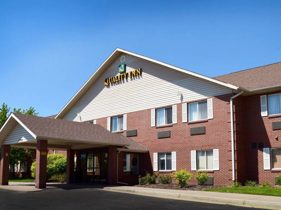 A brick building with a covered entrance and a sign reading "Quality Inn".