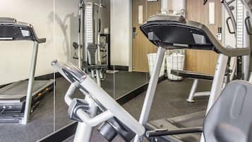 A gym with exercise equipment, a mirrored wall, and a door in the background.