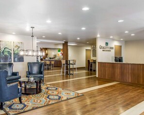 Un hall d’hôtel comprenant un comptoir d’accueil, un espace salon et un coin repas.