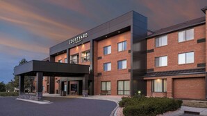 Ein Courtyard by Marriott Hotel mit Ziegelaußenwand, zahlreichen Fenstern und einem überdachten Eingangsbereich.