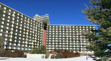 Un hotel grande de varios pisos con fachada enrejada, múltiples balcones y una entrada central.