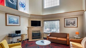 A hotel room with a fireplace, a TV, a desk with a computer, and two sofas. - Econo Lodge North Academy (Colorado Springs)