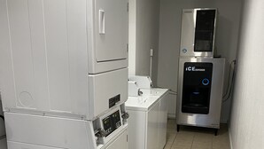 A laundry room with a large washer and dryer, a compact dryer, and an ice dispenser.