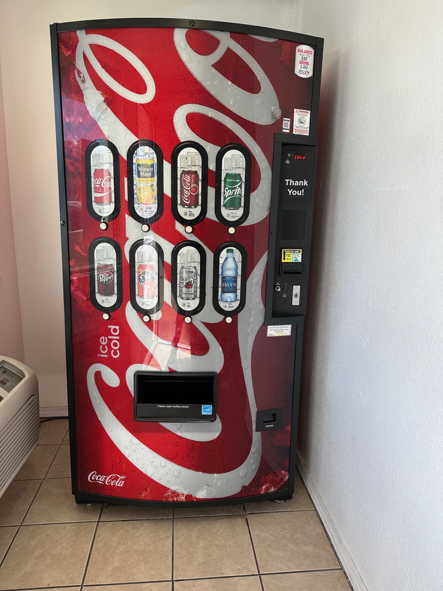 A Coca-Cola branded ice cold beverage vending machine with multiple drink options.