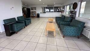 A reception area with teal patterned sofas, a wooden coffee table, and a reception desk.