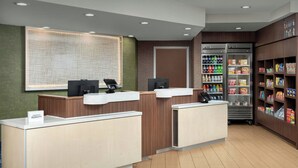 A hotel reception area with a counter, a map on the wall, a refrigerator stocked with beverages, and shelves with snacks. - Fairfield Inn & Suites by Marriott Albuquerque Airport (Albuquerque)