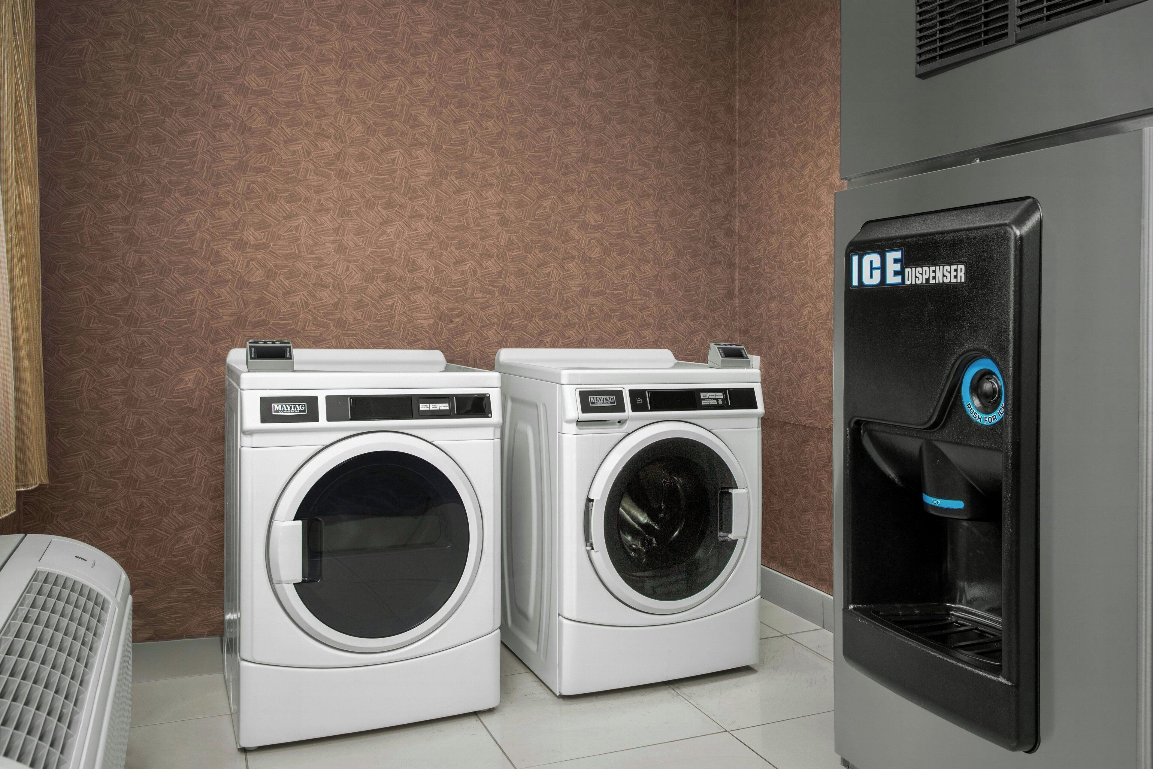 A laundry area with two white washing machines and a black ice dispenser.
