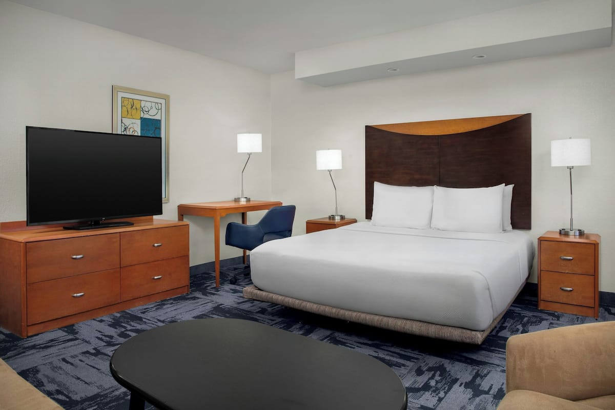 A hotel room with a bed, a desk, a television, and a chair.