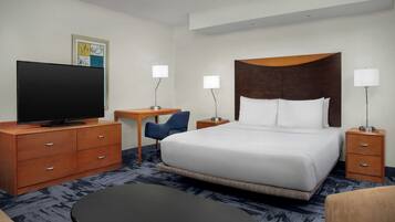 A hotel room with a bed, a desk, a television, and a chair.